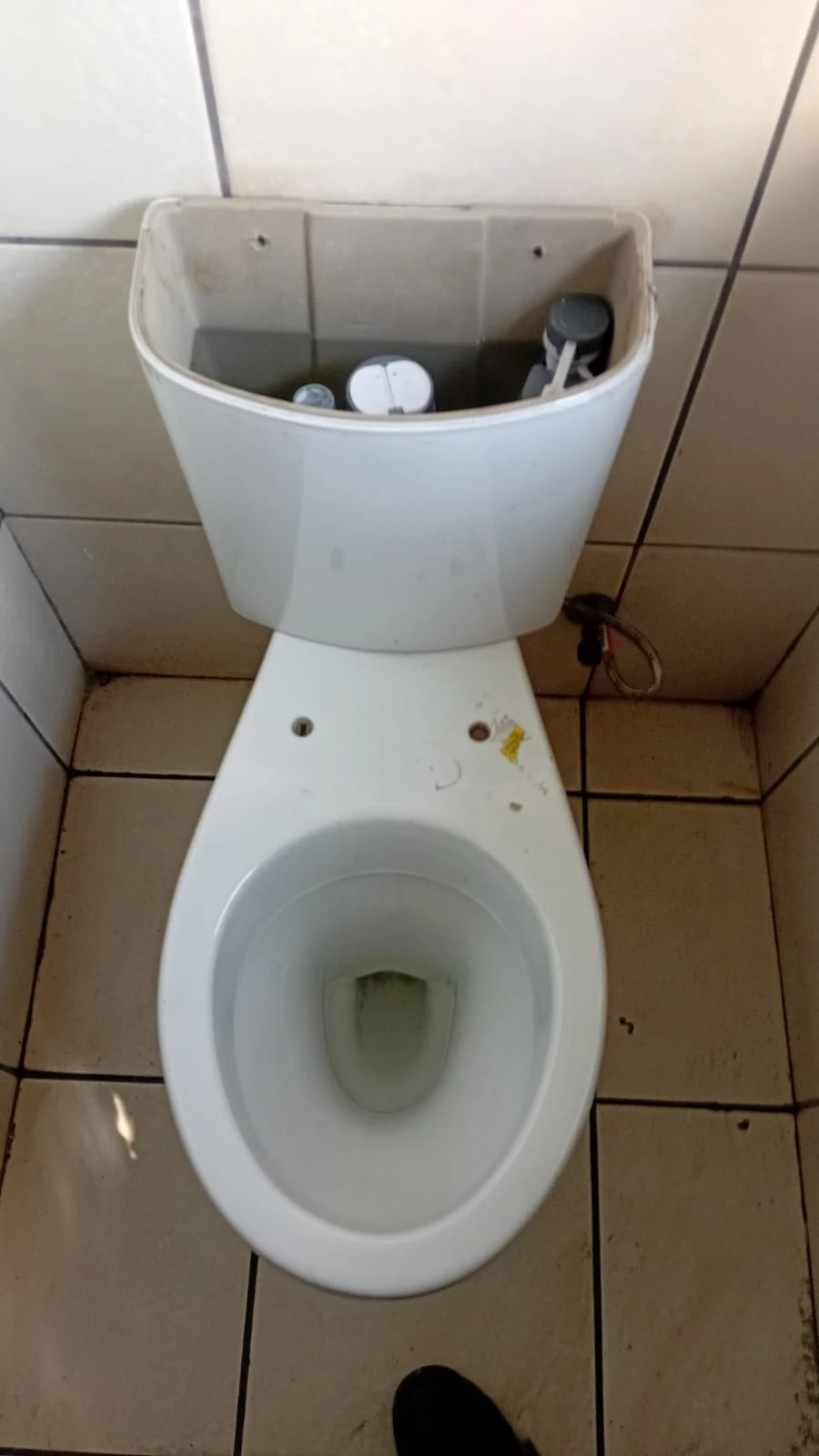 Toilet cistern opened during a blocked-toilet assessment to check flush components and water level.